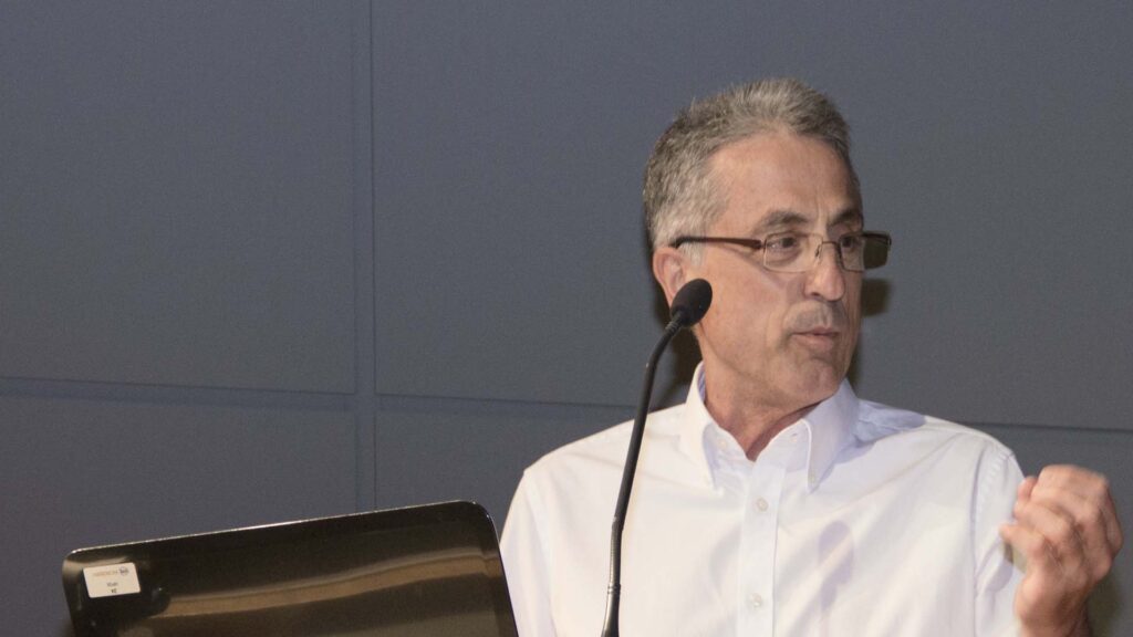 Γιάννης Καπλανέλης καυκάσιος με λευκό πουκάμισο σε στιγμιότυπο από ομιλίες συνεδρίου