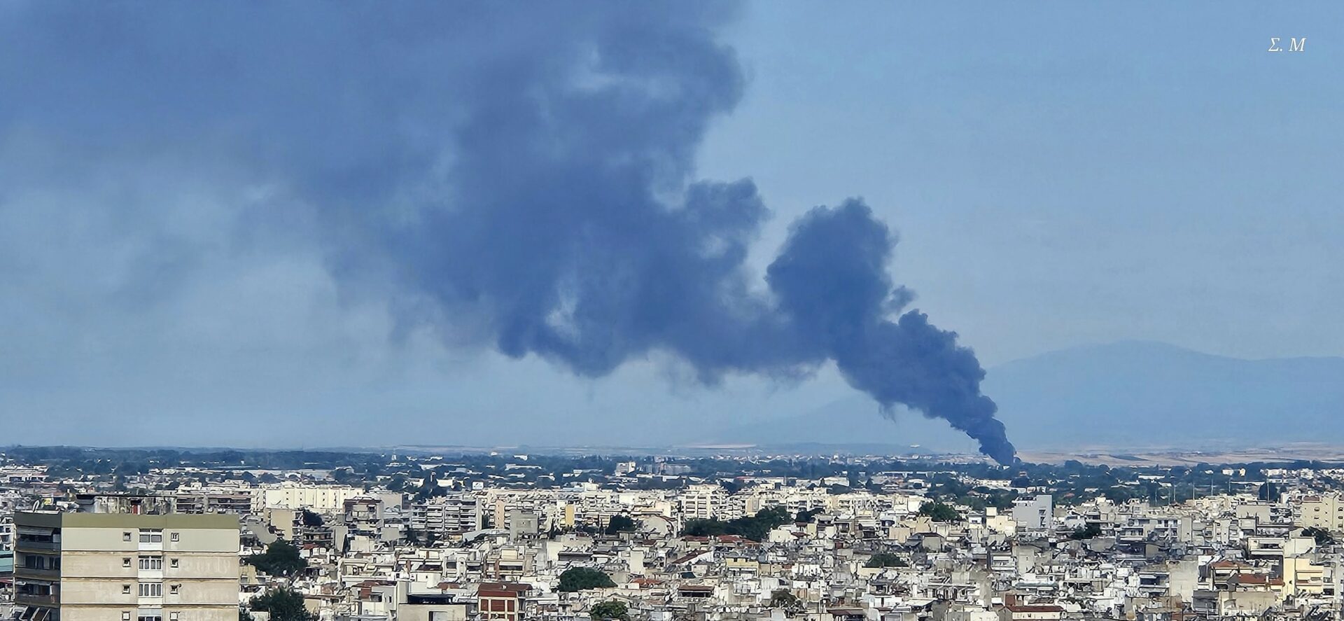 φωτογραφία από πόλη, στον ουρανό φαίνεται καπνός από φωτιά. 